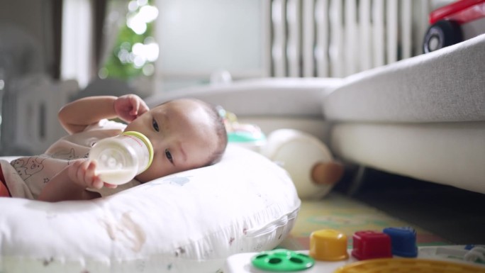 男孩在家里的婴儿床上自己喂奶