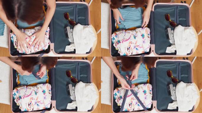 幸福亚洲女旅行家打包布的东西在手提箱准备去暑假旅行在家里的客厅里，女人打包手提箱暑假旅行