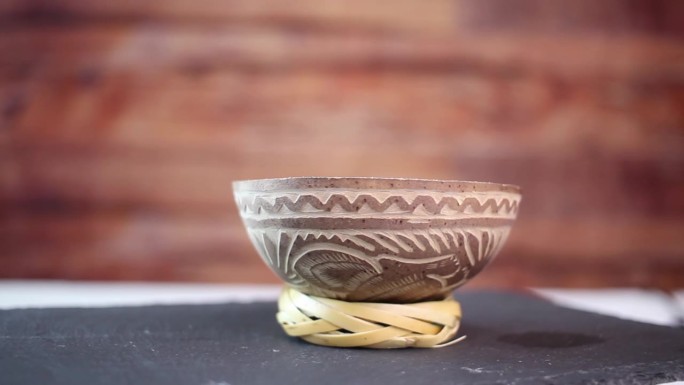 传统的墨西哥杯龙舌兰酒或梅斯卡尔，葫芦与土著雕刻，在石板上旋转