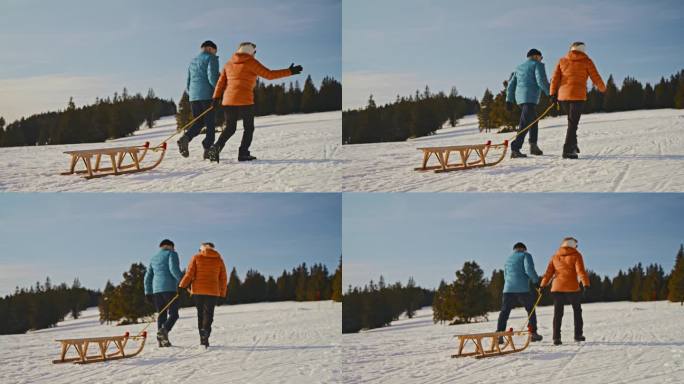 一对老年夫妇正拉着雪橇上雪坡