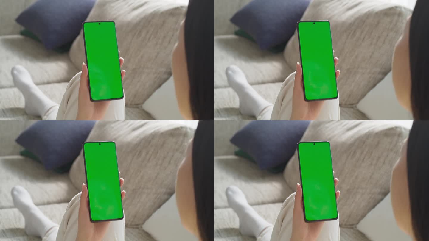 匿名年轻女性使用带有绿屏模拟显示屏的智能手机。在舒适的现代家庭环境中浏览互联网，查看社交媒体网络。越