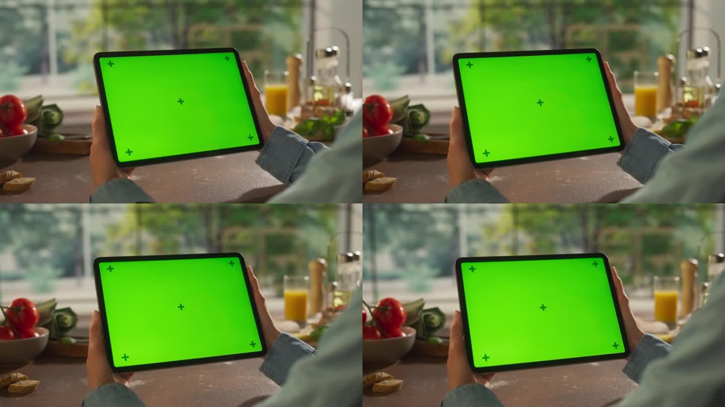 一名匿名女子手持平板电脑，背景是厨房的桌子。数字设备与绿色屏幕色度键模板的数字营销，在线服务，应用程