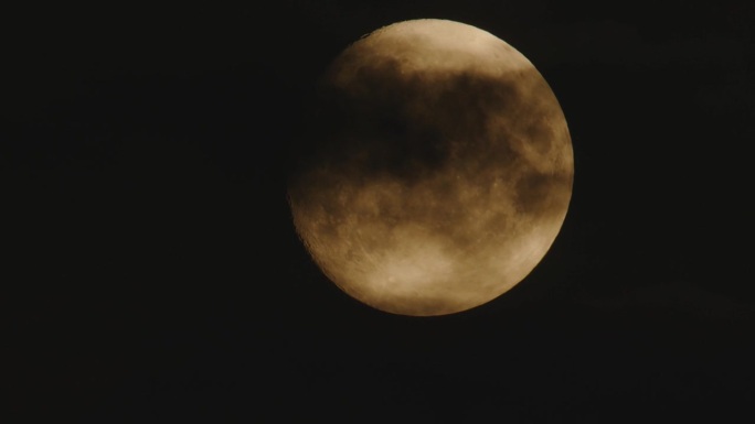 满月在夜空中移动，伴随着小朵云。