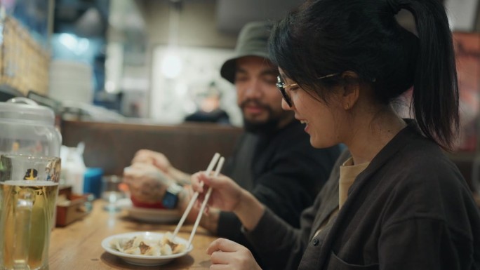 一对亚洲游客夫妇坐在日本餐厅吃拉面。