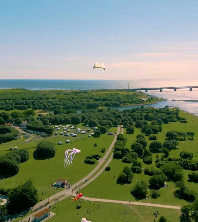 垂直无人机拍摄的风筝滑板飞过草坪和地平线上的蓝天