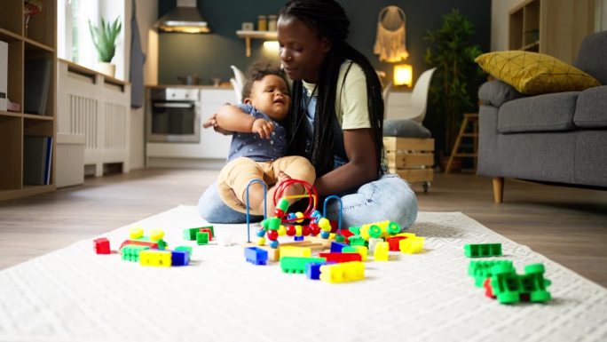 母亲和她的小黑人儿子在家里玩积木玩具