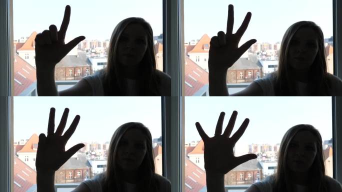 窗边的年轻女孩伸出拳头，张开手掌，用手指数到五