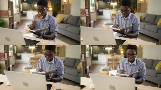 在大学宿舍里，一名非裔美国男学生一边用笔记本电脑上网学习