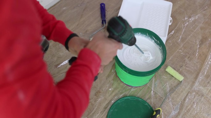 男油漆工在桶里混合颜料