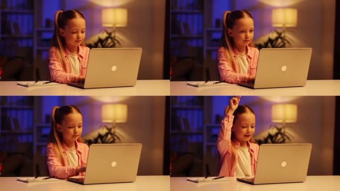 一个可爱的小女孩坐在客厅的桌子旁使用笔记本电脑。孩子示范性地按下按钮，对结果非常满意，像敲鼓一样敲打