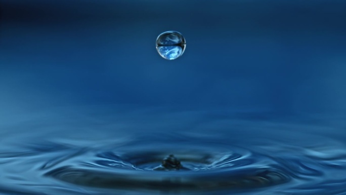 水滴落入深蓝色的水中，在水面上反弹