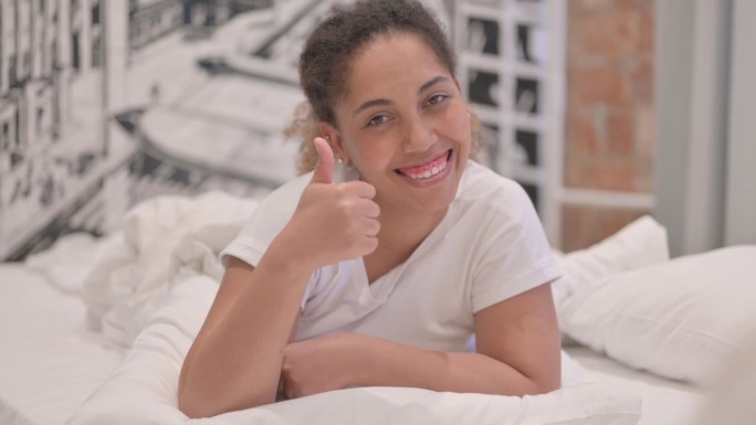 非裔美国妇女趴在床上竖起大拇指