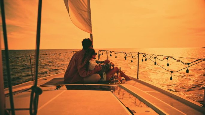 一对异性恋情侣坐在帆船甲板上欣赏大海