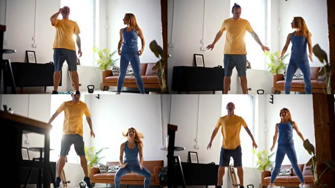 SLO MO Fit年轻夫妇在家锻炼时做深蹲跳，一起在客厅锻炼。他们停顿了一下，笑了笑才继续说下去。