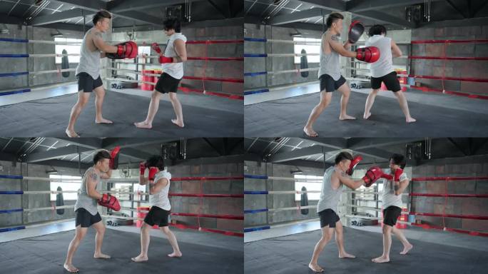 两名亚洲中年男子拳击手在健身俱乐部进行体育训练时正在拳击场上比赛。两名男拳击手在拳击场内比赛。训练战
