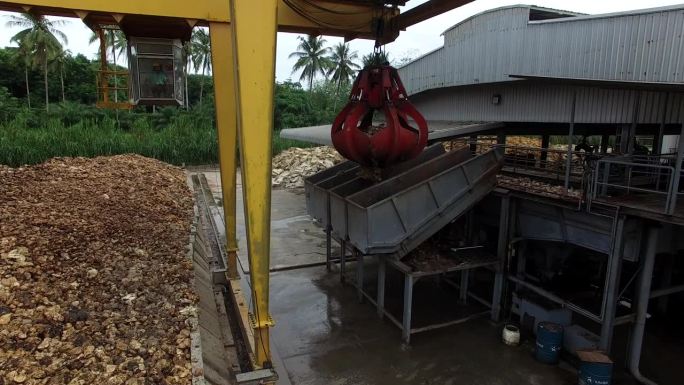 干燥后的天然生胶，用机械抓斗工业机在工厂室外区堆放在水泥地面上。