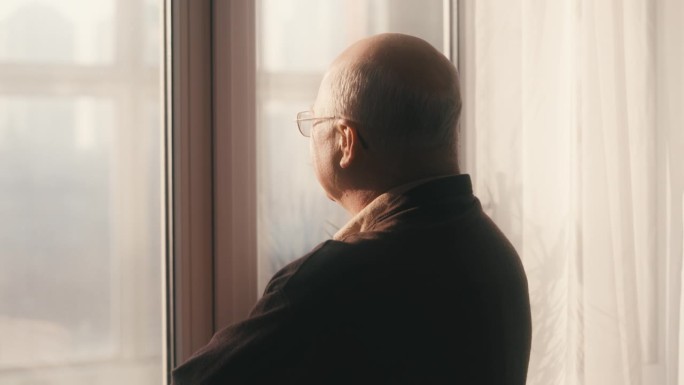 戴着眼镜的快乐老人望着窗外，回忆着美好的时光