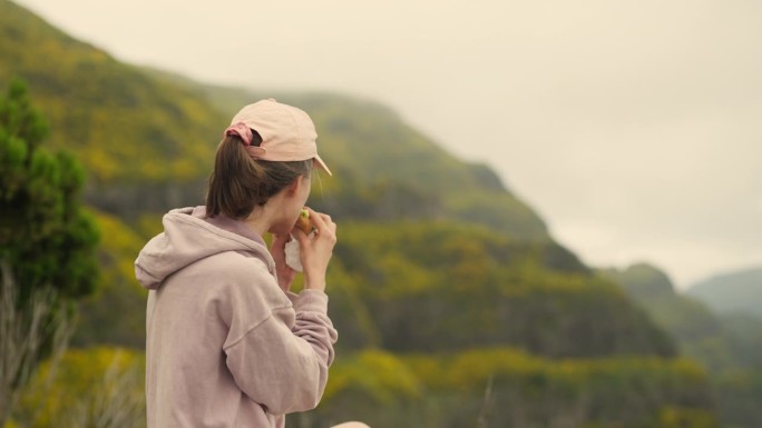 一个女人坐在世界之巅。看山谷的景色。