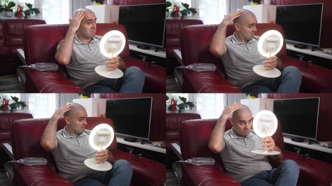 男性癌症患者在家中因化疗脱发后看着镜子中的自己