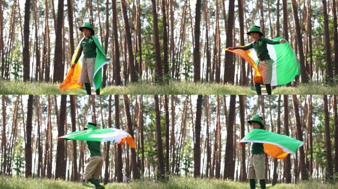 有趣的小男孩戴着小妖精的帽子，穿着小妖精的衣服，手里拿着一面巨大的爱尔兰国旗在转圈。