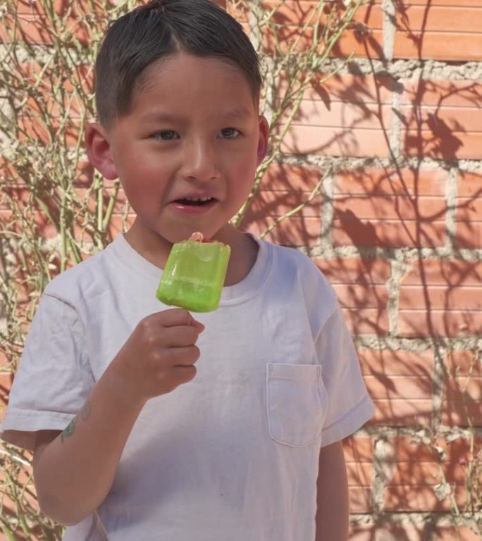 拉丁男孩在玻利维亚拉巴斯炎热的夏日吃冰淇淋的垂直视频