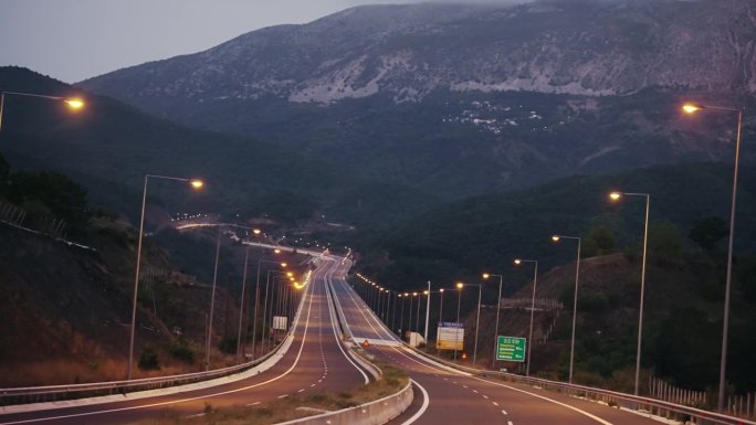 个人视角的快速公路驾驶沿着傍晚的高速公路在黄昏。从车窗前看路。