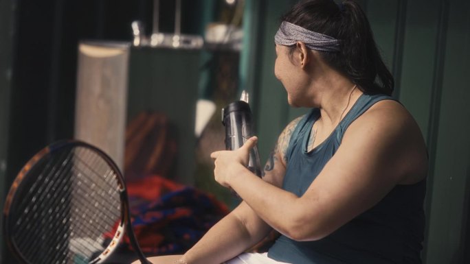 口渴的亚洲中国女网球运动员赛后喝水