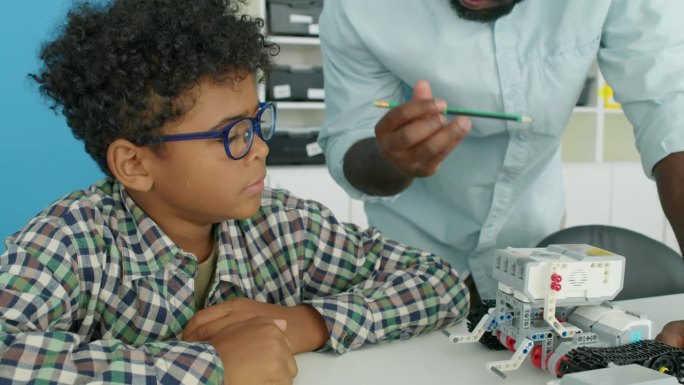 黑人男老师向小男孩展示机器人模型
