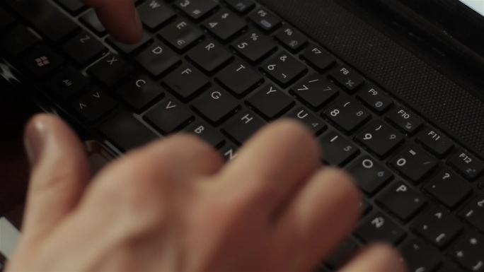 手提电脑键盘上的男人之手。关闭了。
