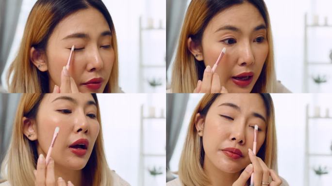 亚洲女博主在家录制化妆教程视频，用睫毛刷在眼睑上涂眼影或亮片，并在网站或社交媒体上向订阅者播放