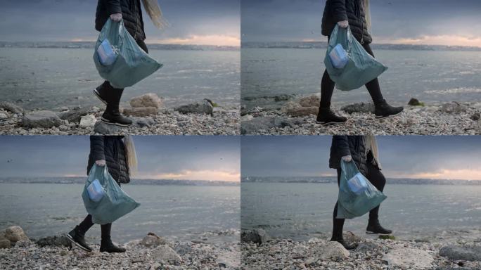 年轻的女志愿者沿着岩石海岸行走，捡起垃圾和碎片，把它们放在垃圾袋里。环保主义的概念，海滩清理，保护自