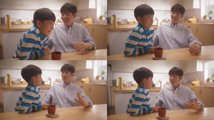 父爱的画像:韩国年轻人和他的儿子坐在家里聊天，开玩笑，亲密无间。快乐的男孩和他的父亲分享和讨论他们的