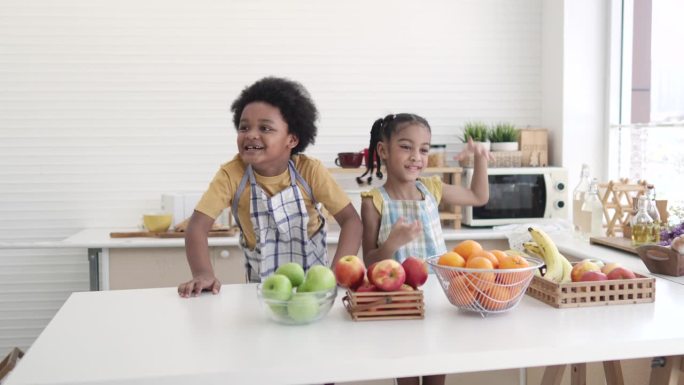 快乐的小男孩和小女孩在厨房里吃水果