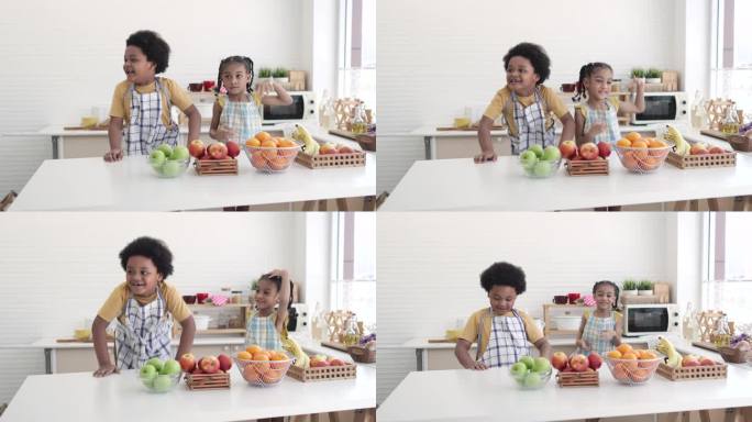 快乐的小男孩和小女孩在厨房里吃水果