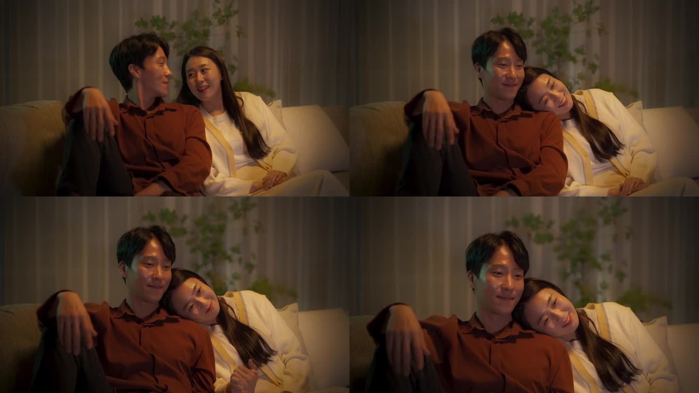 一对年轻的韩国夫妇在家里一起坐在沙发上度过时光的肖像。美丽的女人把头靠在男友的肩膀上，在客厅里看精彩