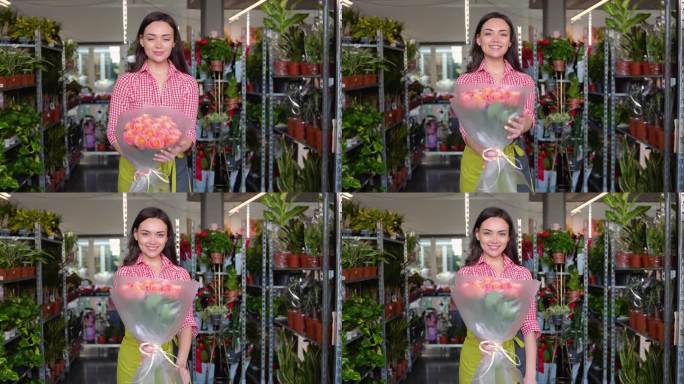 开朗迷人的年轻女花商站在花店里，手里拿着一束玫瑰花。女花商向客户卖花