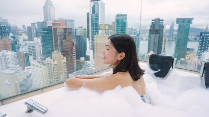 来香港旅游的女孩在私人屋顶房间里泡热水澡。香港的高楼大厦。