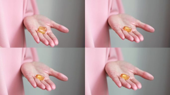 女性手掌中的两粒omega-3营养补充品胶囊或鱼油或维生素D3的特写