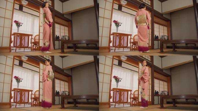 一个美丽的日本模特穿着粉红色和服的肖像。年轻迷人的女性站在家里的传统室内。女人看着镜头，慢慢转过身来