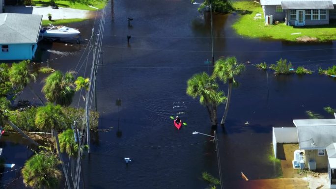 独木舟漂浮在被飓风伊恩包围的街道上，洪水淹没了佛罗里达居民区的房屋。自然灾害的后果
