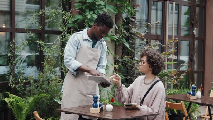 非裔美国咖啡馆工作人员帮助女顾客点餐
