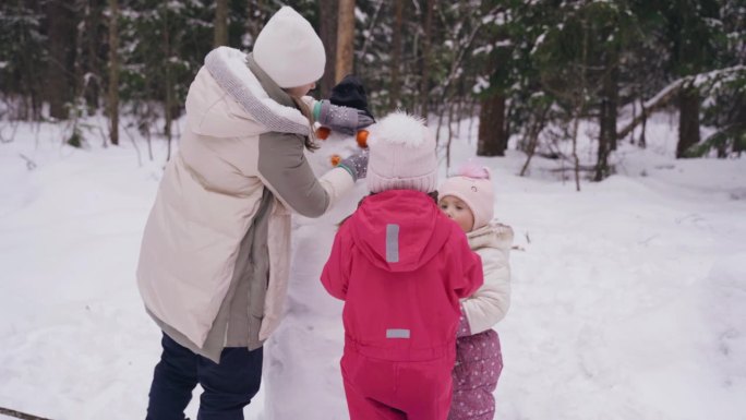 妈妈把目光从橘子转向雪人，她的女儿们帮助她。