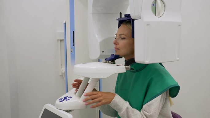 现代牙科诊所用数字牙科x光机站着拍摄3D全景牙齿x光的金发女患者跟踪镜头。