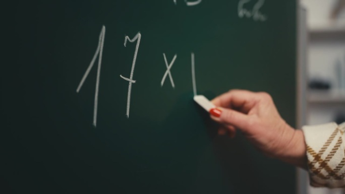 女数学老师在学校黑板上写方程式的特写