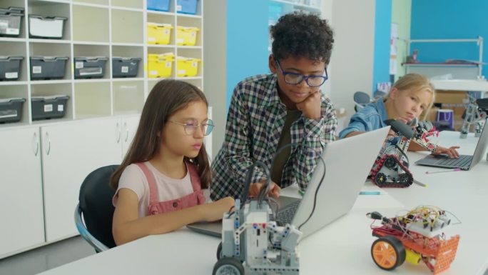 不同的孩子们在爱好俱乐部一起为电动机器人编程