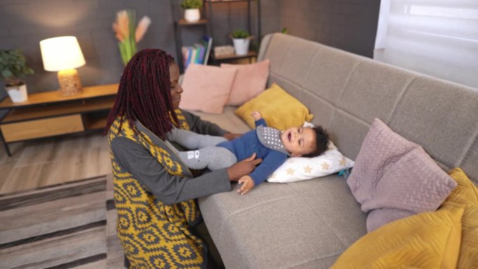 黑人母亲照顾她的小儿子，在沙发上和他玩耍