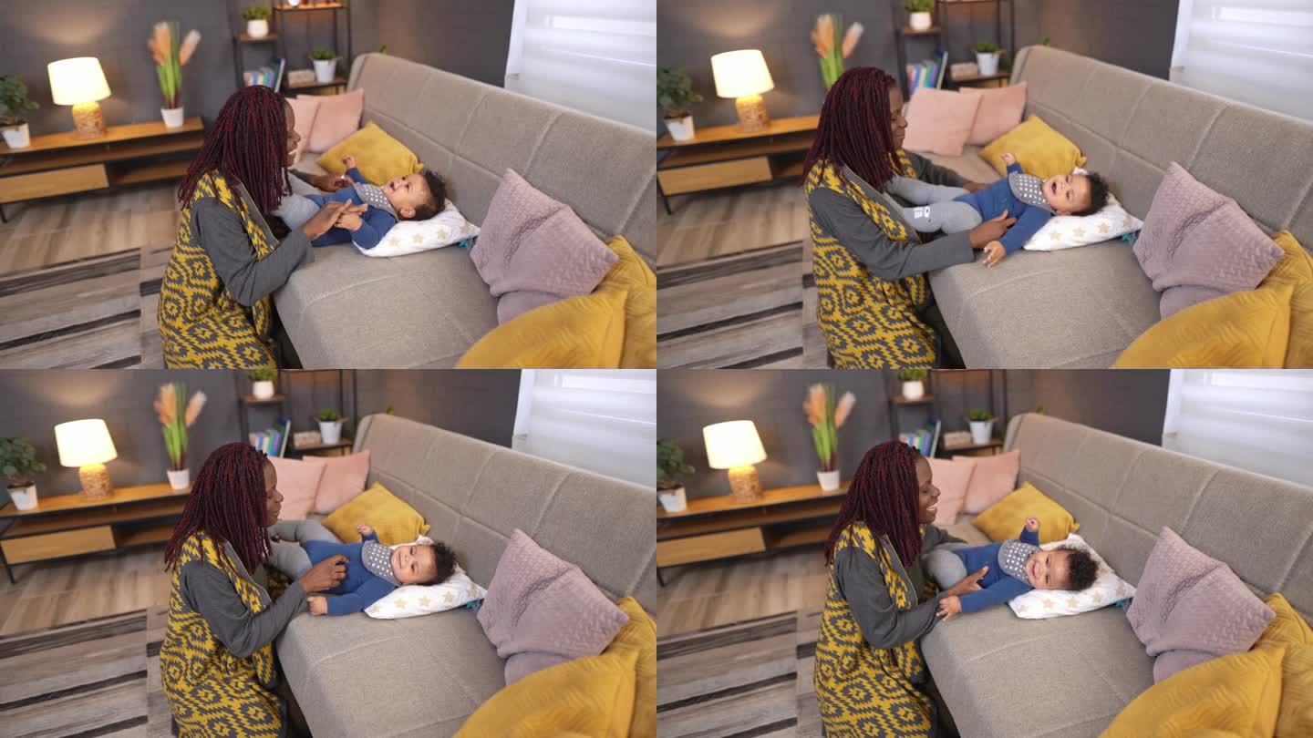 黑人母亲照顾她的小儿子，在沙发上和他玩耍