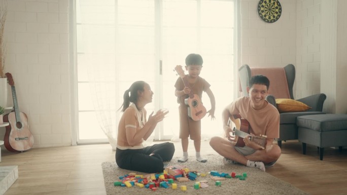 和谐的家庭学习:亚洲父母和儿子在弹吉他中找到快乐和联系。