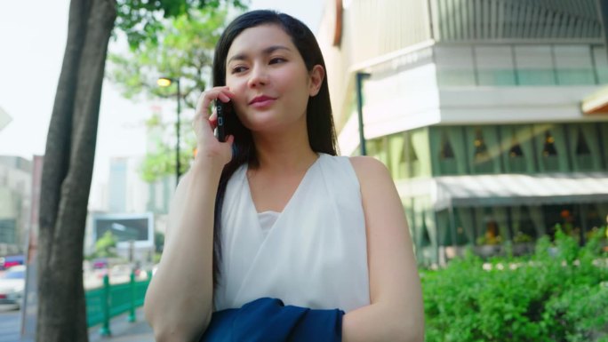 亚洲女商人在城市的户外上班和打电话