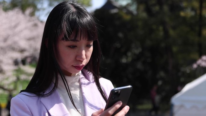 日本女子手持樱花手持智能手机的照片